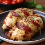 Hasselbackskyckling med ost, tomatsås och pepperoni på en tallrik.