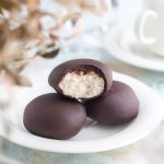 Tre kokosbollar med chokladöverdrag, en är delad för att visa fyllningen.