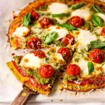 Pizza med broccolibotten, tomater, mozzarella och basilika på en bakplåt.