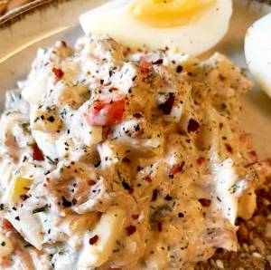 En skål med ägg- och tonfiskröra, dekorerad med kryddor och grönsaker.