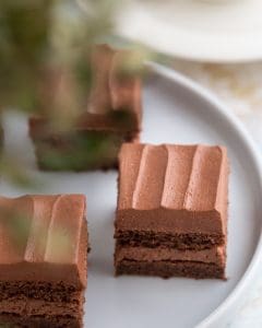 Tre bitar av chokladtårta med krämig chokladfrosting på en vit tallrik.