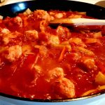 En gryta med köttbullar, tomatsås och grönsaker i en stekpanna.
