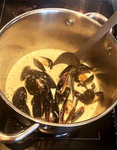 Kastrull med musslor i en krämig sås på en spis.