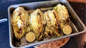Fyra halvor av grillad kål i en ugnsform med skivor av citron.