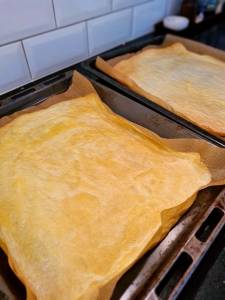 Två plåtar med omelettwraps på bakpapper i en ugn.