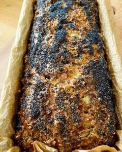 Långt bröd täckt med vallmofrön, bakat och placerat i en pappersform.