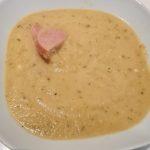 En skål med vitkål- och zucchinisoppa, med en bit korv synlig på ytan.