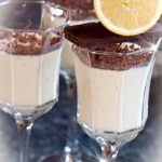 Tre glas med citronpannacotta toppad med choklad och en citronskiva på kanten.