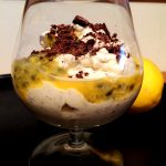 En dessert med vaniljfromage, passionsfrukt och krossad choklad i ett glas.