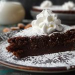 En bit sockerfri kladdkaka med grädde på en tallrik, dekorerad med florsocker.