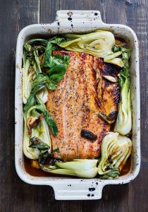En ugnsform med teriyaki lax och pak choi, tillagad med sås och grönsaker.