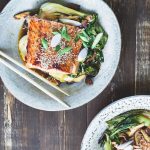 Tallrik med teriyaki lax, pak choi och svamp, garnerad med sesamfrön och grön lök.
