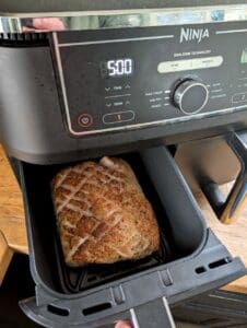 Ninja airfryer med en helstekt kotlettrad inuti korgen, inställd på 500 grader.