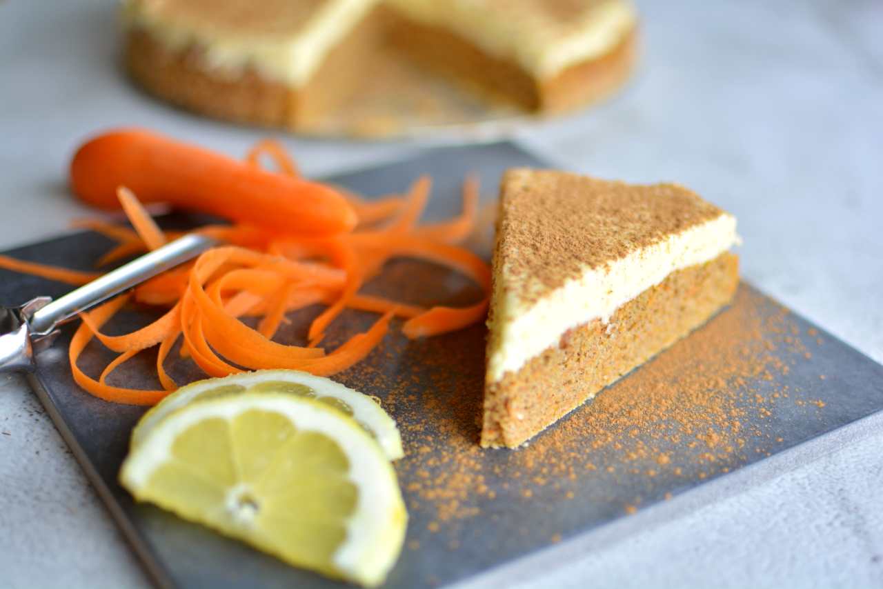 Saftig tårtbotten 7 En bit morotskaka med citron och kanel på en grå tallrik, dekorerad med morotsstrimlor och citronskivor.