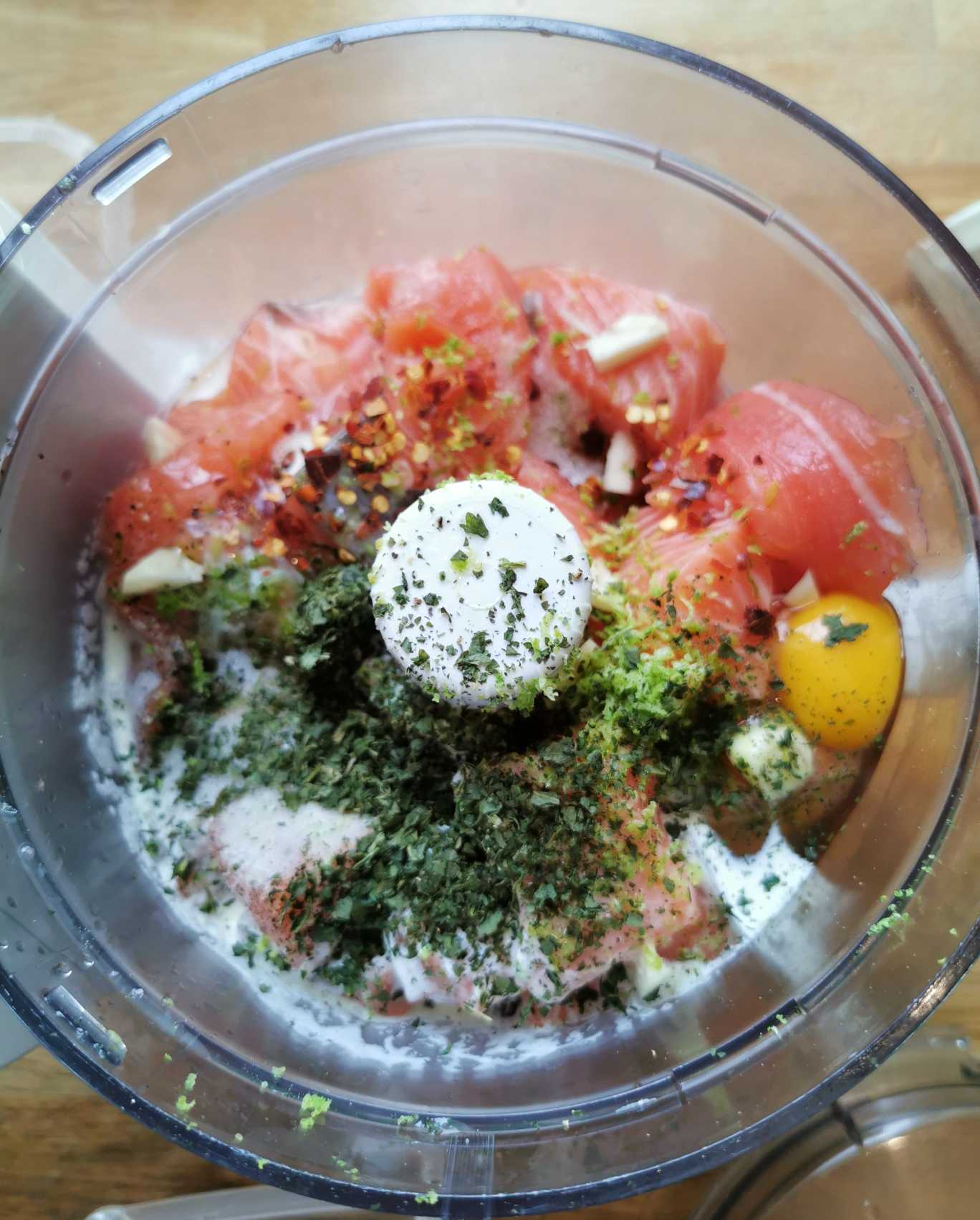 En matberedare med lax, kryddor, vitlök och ägg i en blandning.