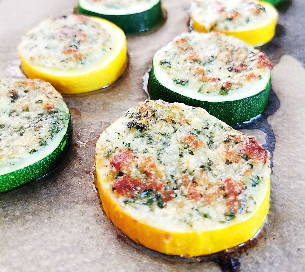 Grillade skivor av zucchini och gul squash med en brödfyllning på en plåt.