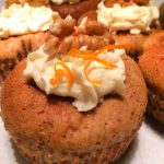 Muffins med gräddtopping och valnötter på toppen, dekorerade med apelsinskal.