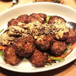 En tallrik med köttbullar toppade med sås och serverade med grönsaker.
