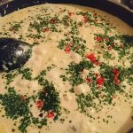 En panna med krämig sås toppad med hackad persilja och röda chili-flingor.