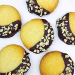 Runda kakor med en halva täckt av mörk choklad och hackade nötter på toppen.