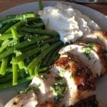 En tallrik med grillad kyckling, gröna bönor och potatismos.