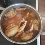 Kastrull med kokande lök och köttbitar på spisen.