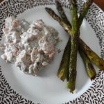 Tallrik med rökt lax blandad med gräddfil och grillad sparris på sidan.