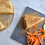 Morotskaka med en bit avskuren, dekorerad med kanel och citron på en grå platta.