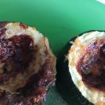Två grillade zucchiniskivor med en gyllenbrun och krispig yta på en grön tallrik.
