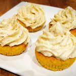 Fyra små kakor med gräddfrosting på en vit tallrik.