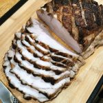 Skivad grillad köttbit med tydliga grillränder på en skärbräda av trä.