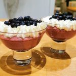 Två skålar med bärdessert toppade med grädde och blåbär.