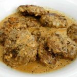 En skål med köttbullar i en krämig sås, serverad i en vit skål.