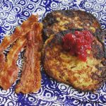 Två potatisplättar med bacon och sylt på en mönstrad tallrik.