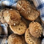Bröd med solrosfrön, delvis skurna, placerade i en blå och vit rutig handduk.