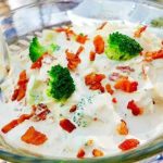 En skål med sallad som innehåller broccoli, bacon och en krämig dressing.