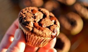 En hand som håller en chokladmuffin med smält choklad på toppen.