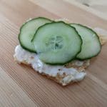 En skiva kex med majonnäs och tre skivor gurka ovanpå.