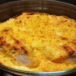 En ugnsbakad köttbit täckt med en gyllene ostsås i en glasform.