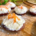 Kakor med kokosfrosting och apelsinskal på en träyta.