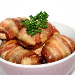 En skål med baconlindade svampar, dekorerad med en kvist persilja.