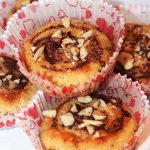 Muffins med kanel och hackade nötter i pappersformar på en tallrik.
