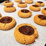 Kakor med en chokladfyllning i mitten, placerade på ett bakplåtspapper.
