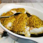 Ugnsbakad fiskfilé täckt med senapssås i en vit ugnsform.