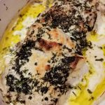 Grillad fiskfilé med örter och olja i en vit ugnsform.