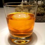 Ett glas med orange vätska och en stor isbit i mitten.